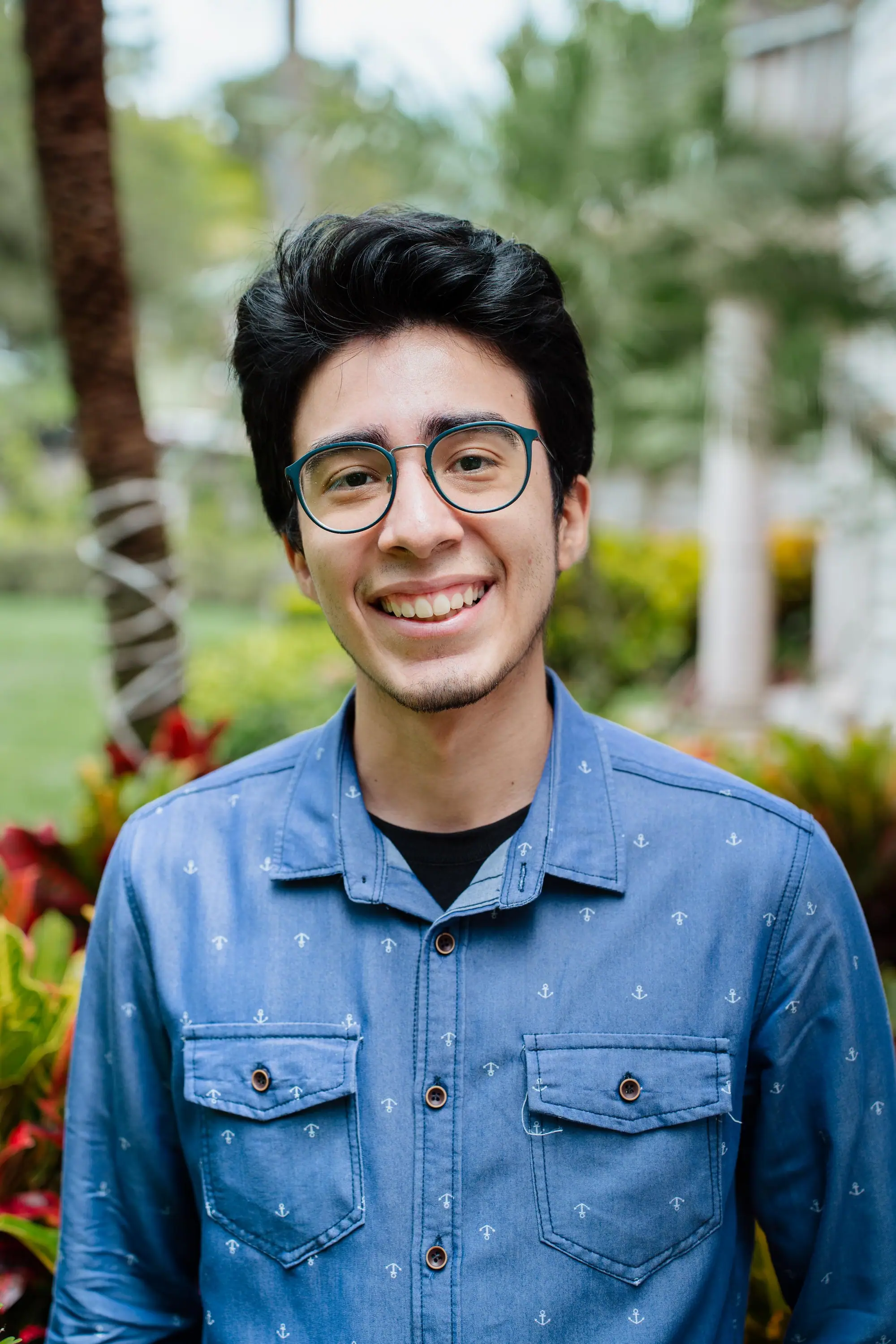 Portrait of Bryan Martinez in a blue button up shirt smiling.